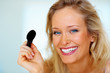 Closeup portrait of a happy beautiful woman applying make up