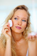 Portrait of a beautiful young woman applying blush