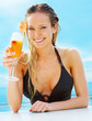 Happy young woman having a mocktail by the swimming pool