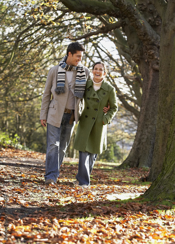 Photo: Couple outdoors arm in arm laughing in a park Couple outdoors arm in arm laughing in a park