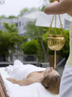 Young woman in spa with oil being poured on forehead