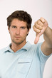 Young man with thumbs down, portrait, close-up