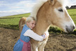 Girl (7-9) embracing pony, close-up