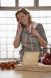Mature woman in kitchen, using mobile phone