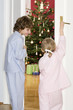 Girl and boy (3-7) standing at door watching Christmas tree, rear view