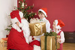 Children (3-7) receiving presents from Santa, smiling