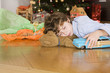 Boy sleeping under Christmas tree, holding toy car