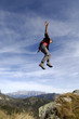 Man jumping over mountains, arms out, side view