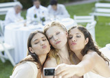 Photo: Three women at an outdoor party taking a self-portrait with a digital camera and puckering up Three women at an outdoor party taking a self-portrait with a digital camera and puckering up