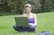 Foto: Junge Frau telefoniert über Notebook im Park Junge Frau telefoniert über Notebook im Park