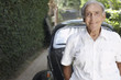 Senior man standing outdoors by car smiling