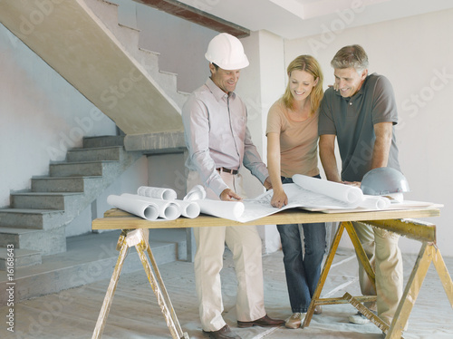 Photo: Construction foreman explaining blueprints to couple Construction foreman explaining blueprints to couple