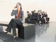 Businesswoman using cell phone away from co-workers