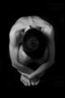 naked man sitting on black background
