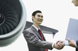 Businessmen shaking hands by airplane