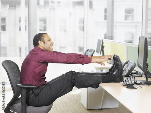 Photo: Businessman stretching at desk Businessman stretching at desk