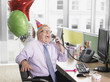 Laughing businessman having birthday party at desk