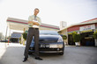 Gas station owner holding clipboard near car