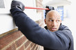 Burglar prying window open with crowbar