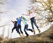 Girls jumping off fallen log in a row
