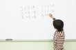 Boy doing multiplication on whiteboard in classroom