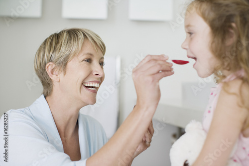 Photo: Mother giving daughter medicine Mother giving daughter medicine
