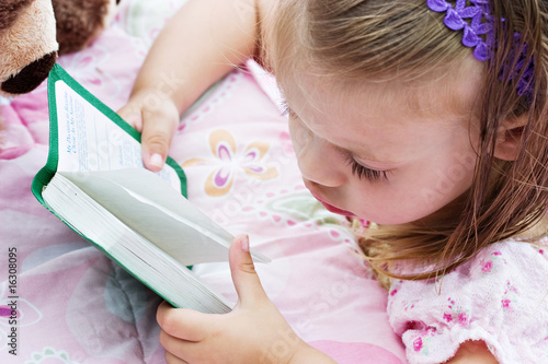 Photo: Child with damp hair is looking at her Bible before bedtime. Child with damp hair is looking at her Bible before bedtime.