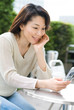 オープンカフェで携帯電話を眺める女性