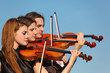 trio of violinists plays against sky trio of violinists plays against sky