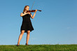 girl stands on grass and plays violin against sky girl stands on grass and plays violin against sky