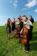 Foto: Group of violinists play standing on grass Group of violinists play standing on grass