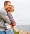 Handsome affectionate young guy embracing his girlfriend outdoor