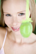 A young blonde woman holding a green Easter egg, close-up