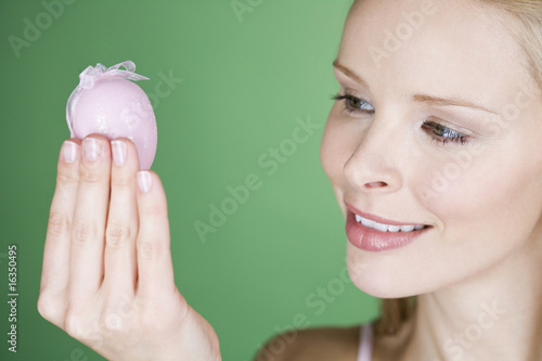 Photo: A young woman looking at a pink Easter egg A young woman looking at a pink Easter egg