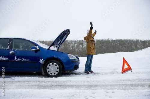 Photo: Stranded woman flagging down car in snow Stranded woman flagging down car in snow