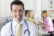 Doctor smiling in examination room with nurse and girl in background