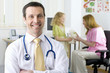 Doctor smiling in examination room with nurse and girl in background