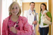 Girl smiling in corridor with mother and doctor in background