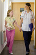 Nurse and girl holding hands and walking down corridor