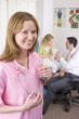 Nurse in office smiling with doctor and girl in background