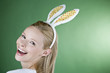 A young blonde woman wearing rabbit ears, laughing