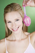 A portrait of a young blonde woman holding a pink Easter egg