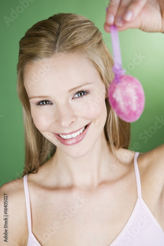 Photo: A portrait of a young blonde woman holding a pink Easter egg A portrait of a young blonde woman holding a pink Easter egg
