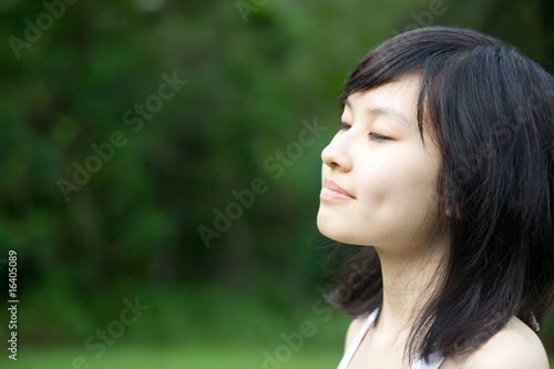 Photo: Beautiful Asian girl enjoying and meditating outdoors Beautiful Asian girl enjoying and meditating outdoors