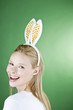 A young blonde woman wearing rabbit ears, smiling