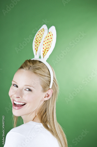 Photo: A young blonde woman wearing rabbit ears, smiling A young blonde woman wearing rabbit ears, smiling