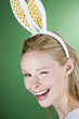 A young blonde woman wearing rabbit ears, winking