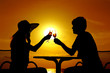 The pair silhouette is held by goblet with wine on a sundown The pair silhouette is held by goblet with wine on a sundown