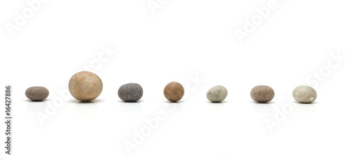 Photo: row of seven pebbles, one larger than the others row of seven pebbles, one larger than the others