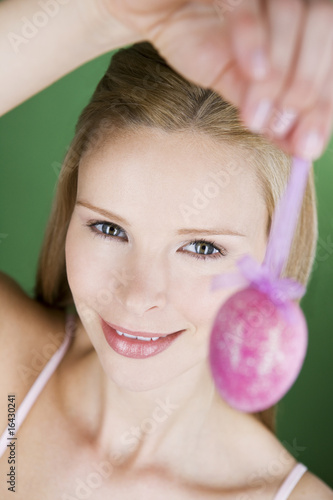 Photo: A portrait of a young blonde woman holding a pink Easter egg A portrait of a young blonde woman holding a pink Easter egg